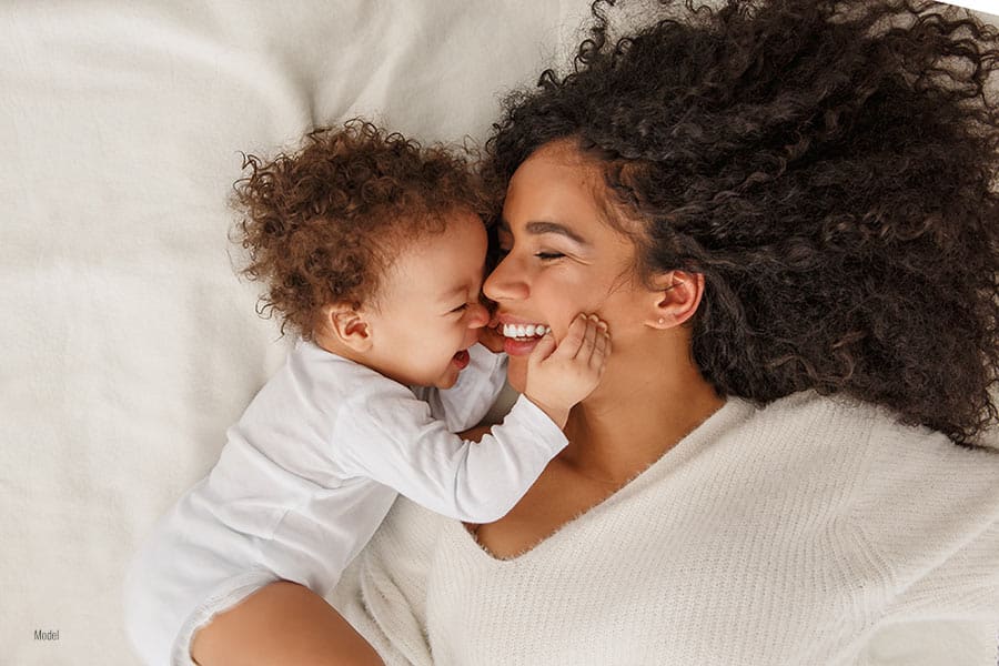 A mother and her child smiling and holding each other in a close embrace.